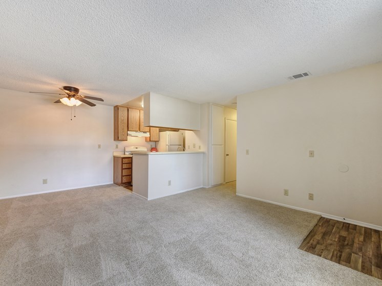 Vacant apartment Entrance and Living Room with views of the kitchen area.  Ceiling fan near the kitchen area